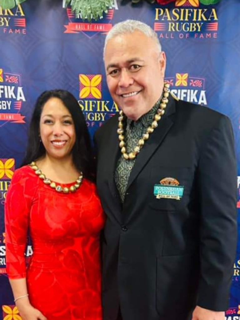Jesse Sapolu taking a photo with woman in red dress